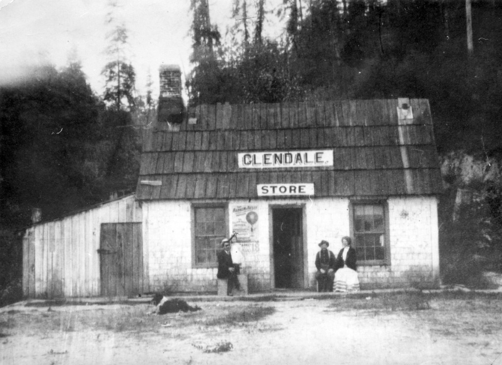 Bill Peterson sitting at the left of the door of the General Store. Peterson was an early landowner and logger.